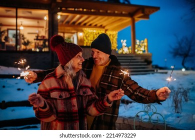 Happy senior couple celebrating new year with sparklers, enjoying winter evening. - Powered by Shutterstock