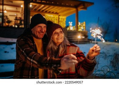 Happy senior couple celebrating new year with sparklers, enjoying winter evening. - Powered by Shutterstock