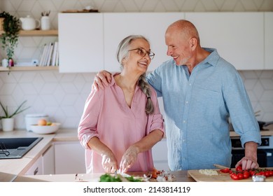 Happy senior couple cooking together at home. - Shutterstock ID 2143814119