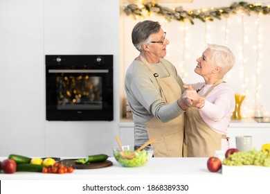 Happy Senior Couple Dancing In Kitchen At Home, Cooking Preparing Christmas Dinner Together And Having Fun. Retired Lifestyle Happiness, Older Family Holidays Concept. Copy Space