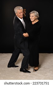 Happy Senior Couple Dancing On Dark Background