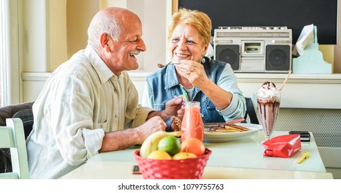 Happy senior couple doing breakfast inside vintage bar restaurant in morning time - Joyful elderly, love and healthy lifestyle concept - Focus on man face  - Powered by Shutterstock