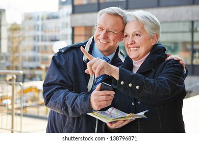 Happy Senior Couple Doing Sightseeing Tour On City Trip With A Map