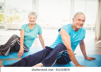 Happy Senior Couple Doing Yoga On Exercise Mat At Home