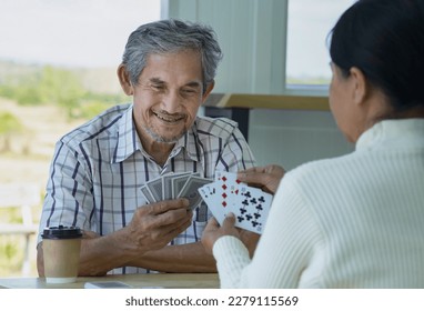happy senior couple enjoy playing cards game together, concept elderly pensioner lifestyle, entertainment, recreation, encourages social interaction, help memory retention 