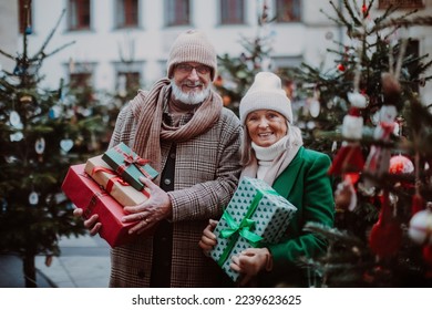 Happy senior couple enjoying christmas market, buying gifts and christmas tree. - Powered by Shutterstock