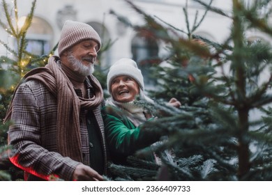 Happy senior couple enjoying christmas market, buying christmas tree.
