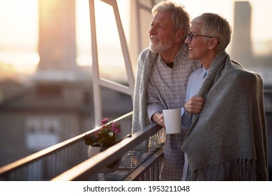 Happy senior couple enjoying morning coffee together on the balcony - Powered by Shutterstock