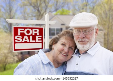 Happy Senior Couple Front Of For Sale Real Estate Sign And House.