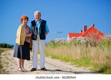 Happy Senior Couple In Front Of Their House