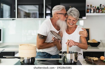 Happy Senior Couple Having Fun Cooking Together At Home - Elderly People Preparing Health Lunch In Modern Kitchen - Retired Lifestyle Family Time And Food Nutrition Concept