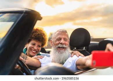 Happy Senior Couple Having Fun On New Convertible Car Roadtrip Taking Selfie With Mobile Smartphone - Travel People Lifestyle Concept 