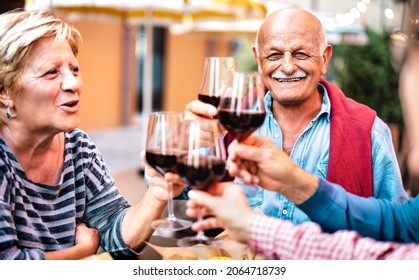 Happy Senior Couple Having Fun Drinking Red Wine With Friends At Dinner Party - Retired People Eating At Restaurant Balcony Together - Dinning Life Style Concept On Warm Filter - Focus On Man Face