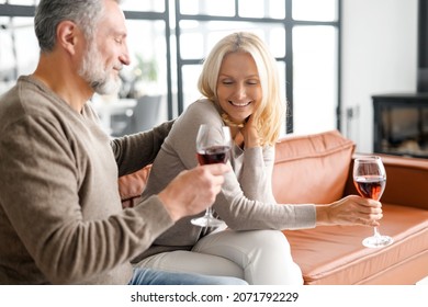 Happy senior couple having fun at home, enjoying time together at home, handsome grey-haired man and beautiful blonde woman drinking wine and laugh and flirting, have a date - Powered by Shutterstock