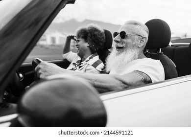 Happy Senior Couple Having Fun In Convertible Car During Summer Vacation - Focus On Man Face - Black And White Editing