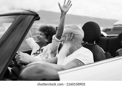 Happy Senior Couple Having Fun In Convertible Car During Summer Vacation - Focus On Man Ear - Black And White Editing