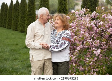 Happy Senior Couple Having Fun In Summer Or Spring Nature Near Sakura Blooming Tree Wearing Ukrainian Embroidered Shirt