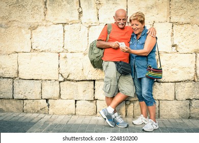 Happy Senior Couple Having Fun With A Modern Smartphone - Concept Of Active Elderly And Interaction With New Technologies - Travel Lifestyle Without Age Limitation - Warm Vivid Filter