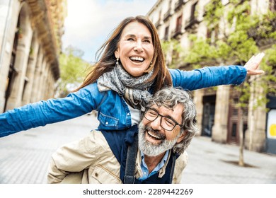 Happy senior couple having fun walking on city street - Two older tourists enjoying together weekend summer vacation - Life style, tourism and romance moments concept - Powered by Shutterstock