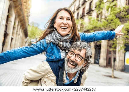 Happy senior couple having fun walking on city street - Two older tourists enjoying together weekend summer vacation - Life style, tourism and romance moments concept
