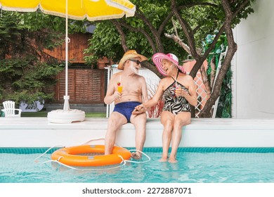 Happy senior couple having party in the swimming pool - Elderly friends releaxing at a pool party during summer vacation - Powered by Shutterstock