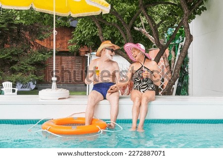 Happy senior couple having party in the swimming pool - Elderly friends releaxing at a pool party during summer vacation