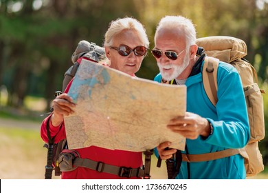 Happy senior couple of hikers looking for destination on the map. Love, people, nature and lifestyle concept. - Powered by Shutterstock