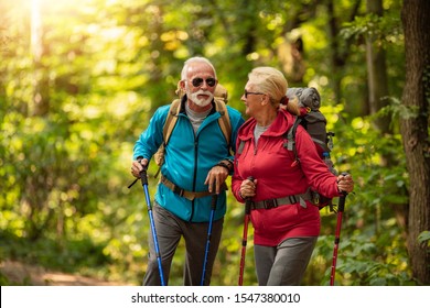 Happy Senior Couple Is Hiking In Forest.Adventure, Travel,hike And People Concept.