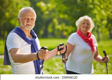 Happy Senior Couple Hiking Together In Summer In Nature