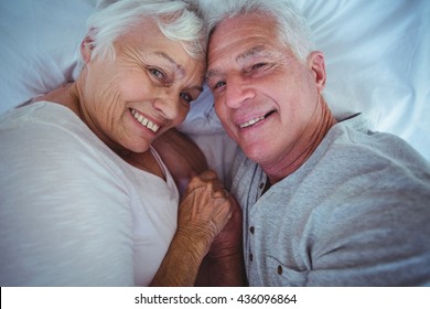 Schönes Ehepaar, das Händchen hält, während es im Zimmer liegt