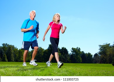 Happy Senior Couple Jogging In The Park.