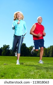 Happy Senior Couple Jogging In The Park.