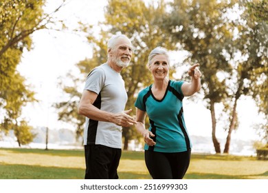 Happy senior couple jogging in the park, smiling and planning their route, inspiring others to prioritize health and wellness by staying active in retirement - Powered by Shutterstock