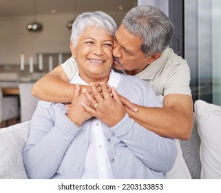 Happy Senior Couple Kiss On Sofa And Smile For Love, Happiness And Trust In Family Home Or House Living Room. Elderly Mexico Man And Woman Or People In Retirement Hug, Kissing And Romance On Couch