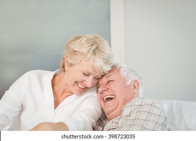Happy senior couple laughing in bed at home