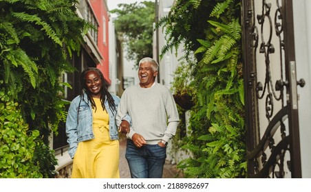 Happy senior couple laughing cheerfully while walking together outdoors. Cheerful senior couple spending some quality time together after retirement. - Powered by Shutterstock