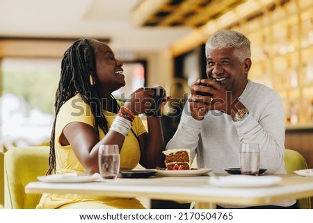 Happy senior couple laughing cheerfully while having coffee together in a cafe. Carefree senior couple having a good time in a restaurant. Mature couple enjoying their retirement together.