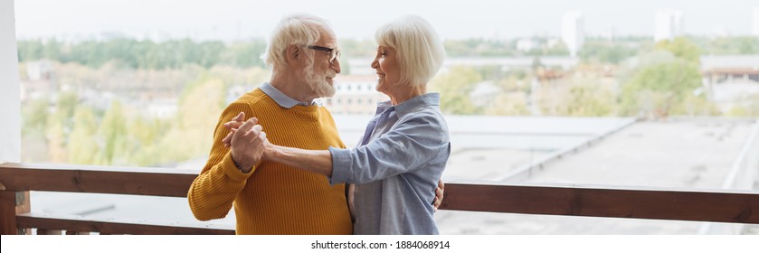 happy senior couple looking at each other while dancing on terrace on blurred background, banner - Powered by Shutterstock