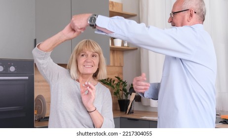 Happy Senior Couple In Love Dancing In The Living Room, In The Kitchen.