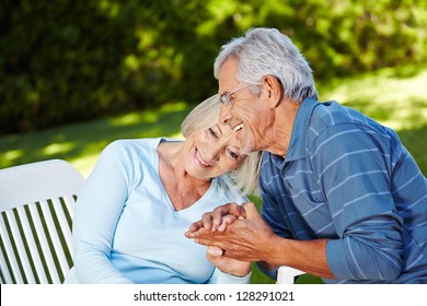 Happy Senior Couple In Love Sitting Outside In A Garden