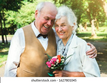 Happy Senior Couple Love Story. Old Couple Is Walking In The Green Park. Grandmother And Grandfather Laughing. Elderly People Lifestyle. Pensioners Together.