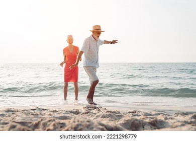 Happy senior couple in love walking and dancing together on the beach having fun in a sunny day, activity after retirement in vacations and summer. - Powered by Shutterstock