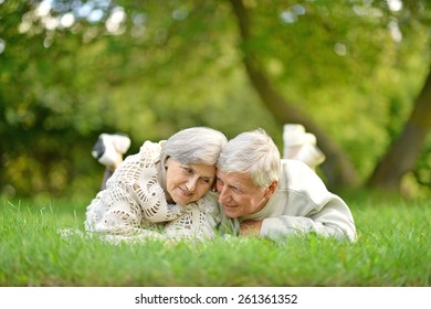 Happy Senior Couple Lying In Par On Green Grass