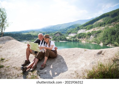 Happy senior couple on hiking trip on summer holiday, using map.