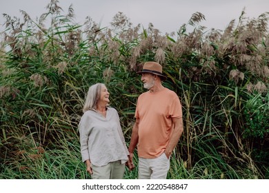 Happy Senior Couple On Walk Near The Lake During Autumn Day.