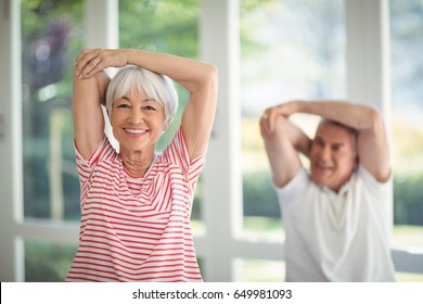 Happy Senior Couple Performing Stretching Exercise At Home