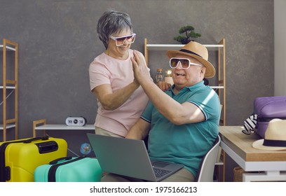 Happy Senior Couple Planning Summer Vacation And Using Laptop. Excited Older Husband And Wife In Hats And Sunglasses Find Perfect Hotel Room And High Five Each Other. Traveling, Online Booking Concept