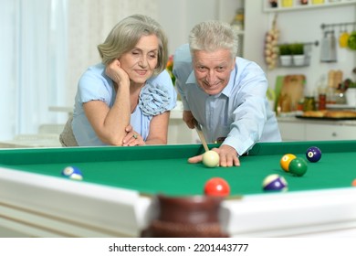 Happy Senior Couple Playing Billiards On Vacation Together In Home