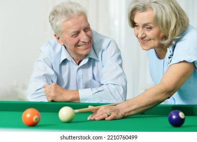 Happy Senior Couple Playing Billiards On Vacation Together In Home