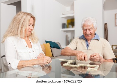 Happy Senior Couple Playing Game Dominoes.
